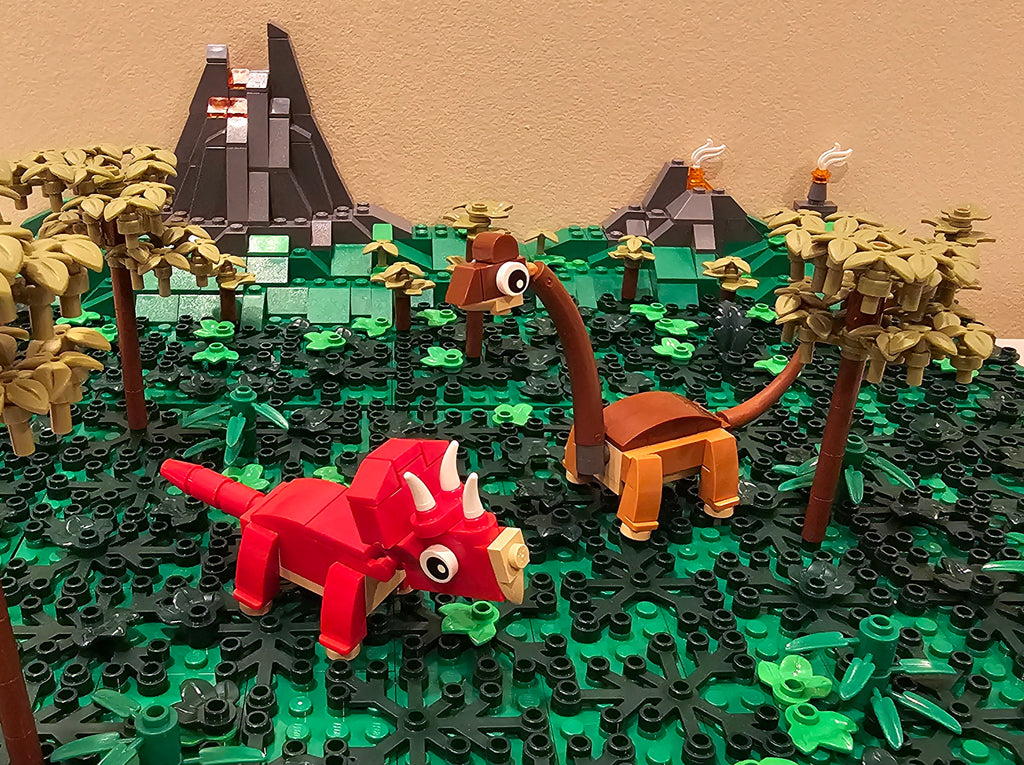 LEGO models of dinosaurs in a prehistoric landscape with trees and mountains.